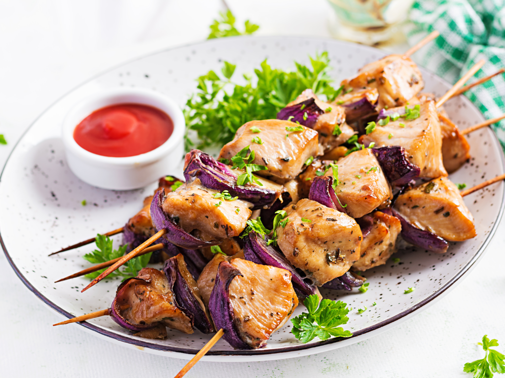 Grilled chicken kebab with red onions on a light table. Grilled meat skewers, shish kebab on light background.